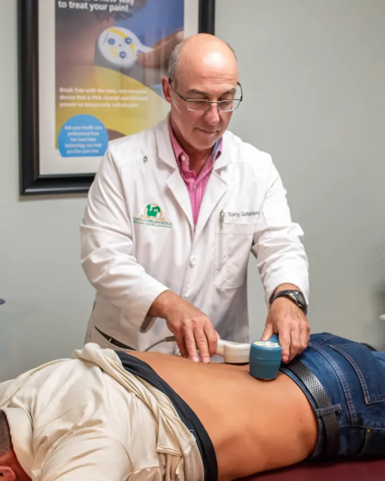 Dr. Anthony Gatelaro using a low-level laser therapy device on a patient’s lower back at Belden Village Chiropractic and Wellness Center in Canton, OH