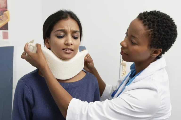 Provider fitting a soft cervical collar on a woman with a neck injury during an exam